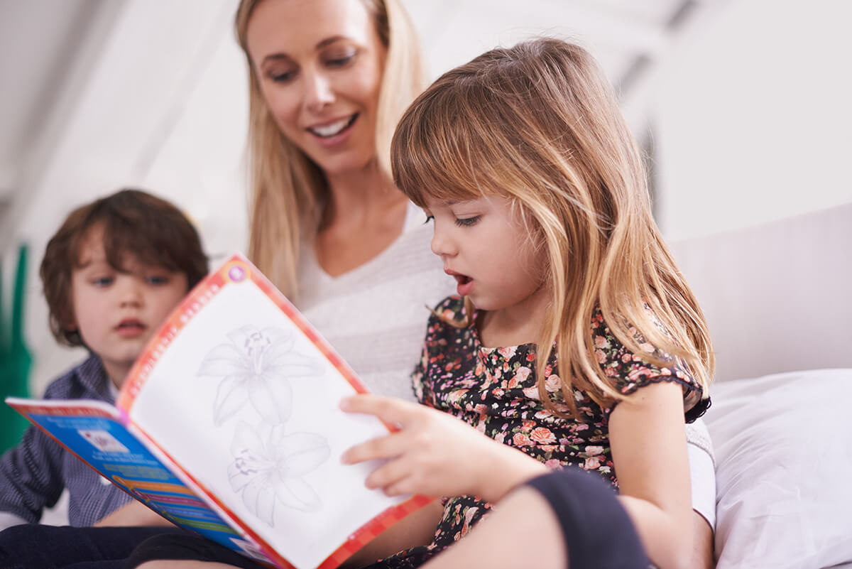 Child reading with parent and sibling