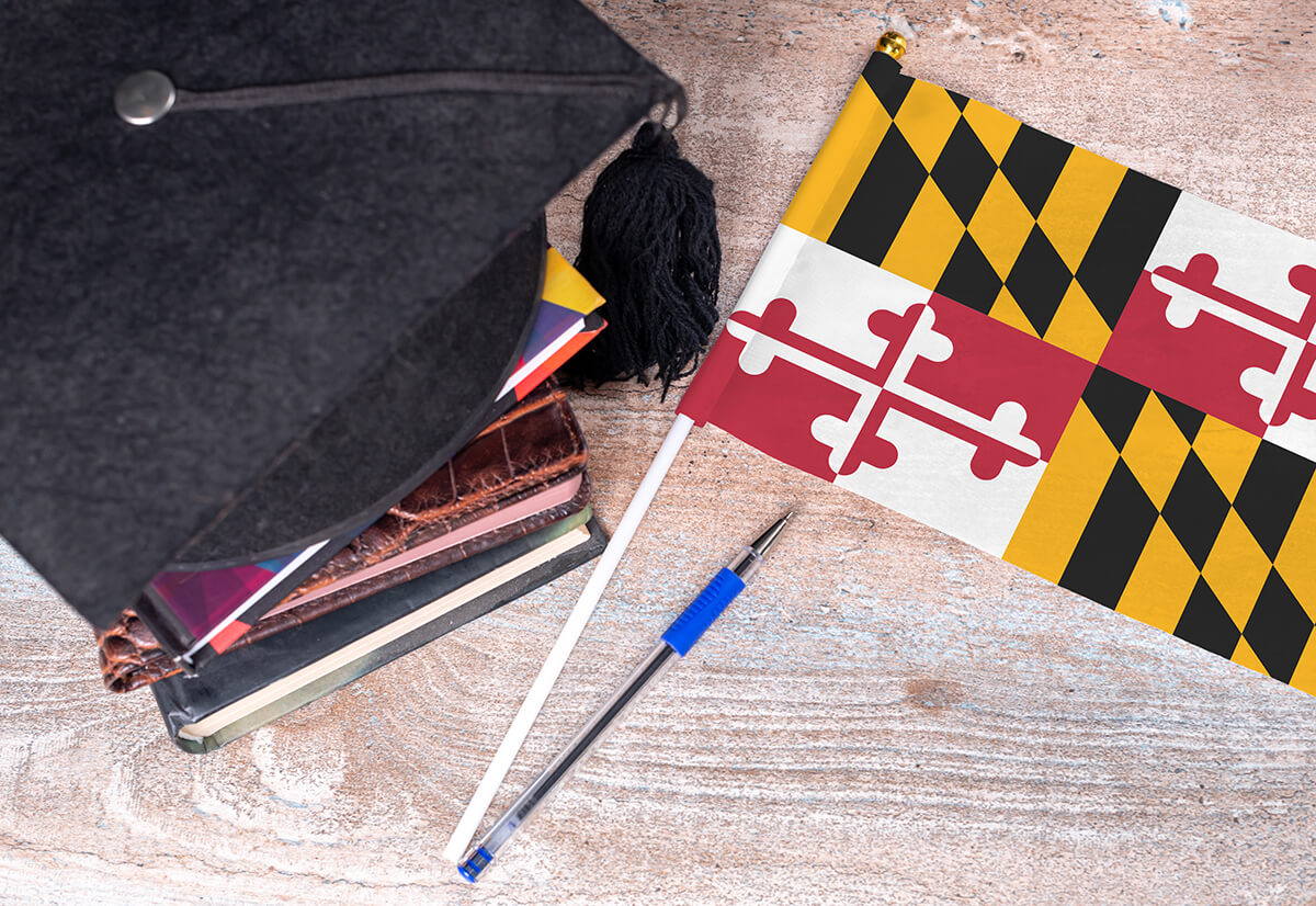 Maryland state flag and graduation cap sitting on books.