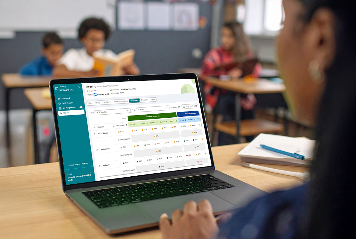 Woman looking at laptop with kids in classroom.