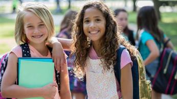 2 girls out side with bookbags
