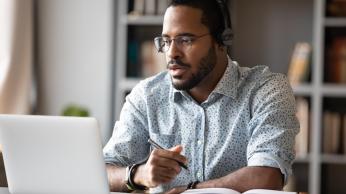 Male teacher on laptop with headphones