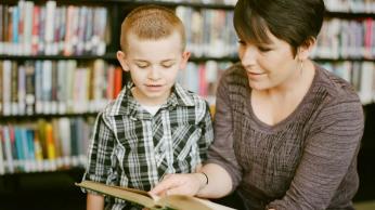 Adult with child looking in a book together.