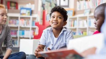 Three kids sitting in a reading circle.