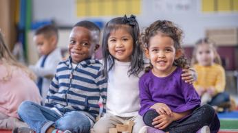 Three young kids posing for the camera together.