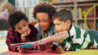 Three students reading a book together.