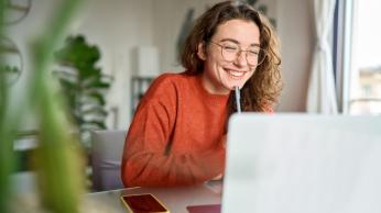 Woman smiling on laptop.