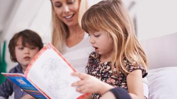 Child reading with parent and sibling