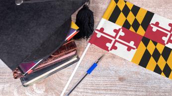 Maryland state flag and graduation cap sitting on books.