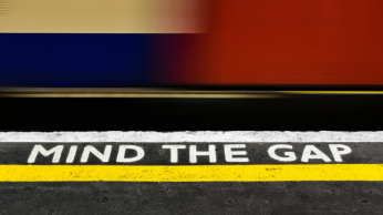 Mind the gap written on the ground of a subway station with the tube whizzing by