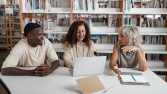 Three people collaborating in a library 