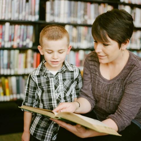 Adult with child looking in a book together.
