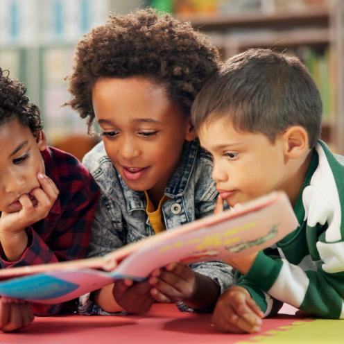 Three students reading a book together.