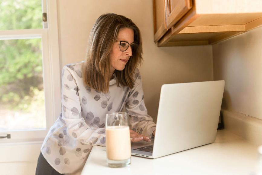 Woman using gray laptop computer in kitchen