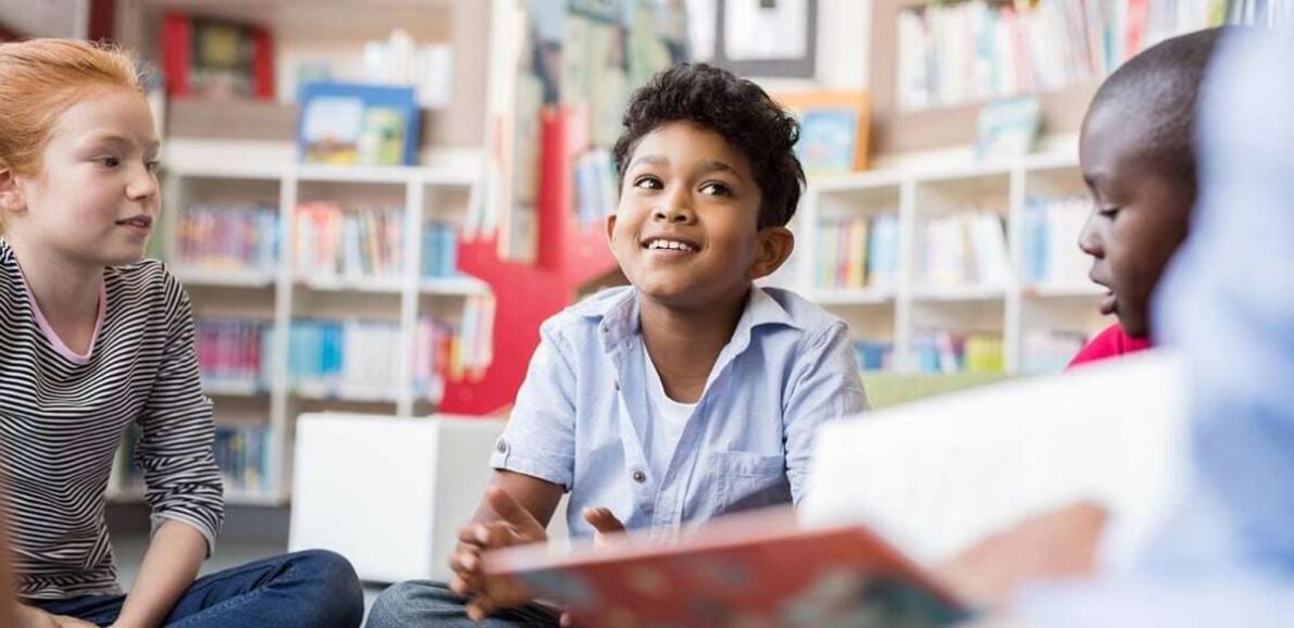 Three kids sitting in a reading circle.
