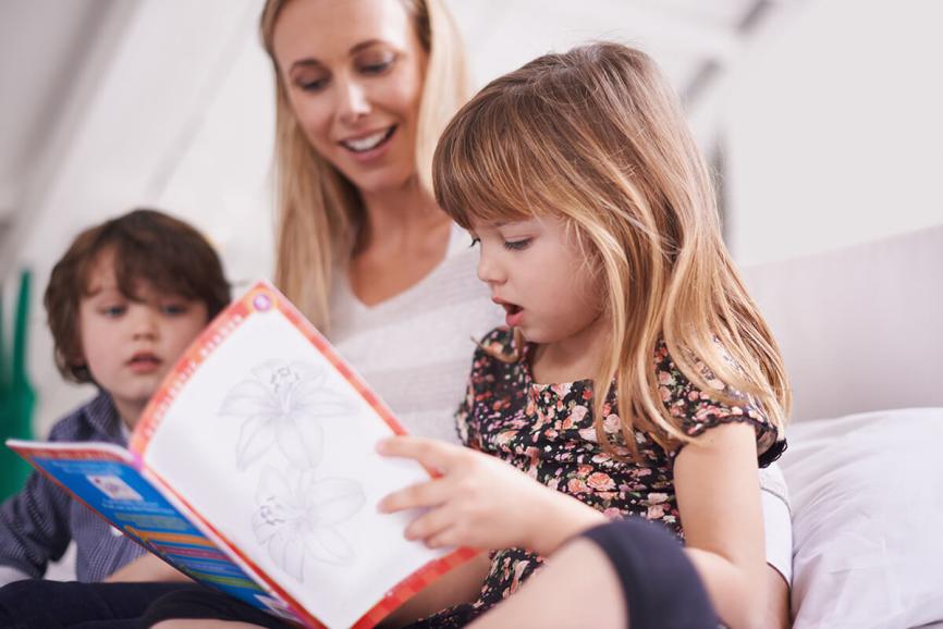 Child reading with parent and sibling