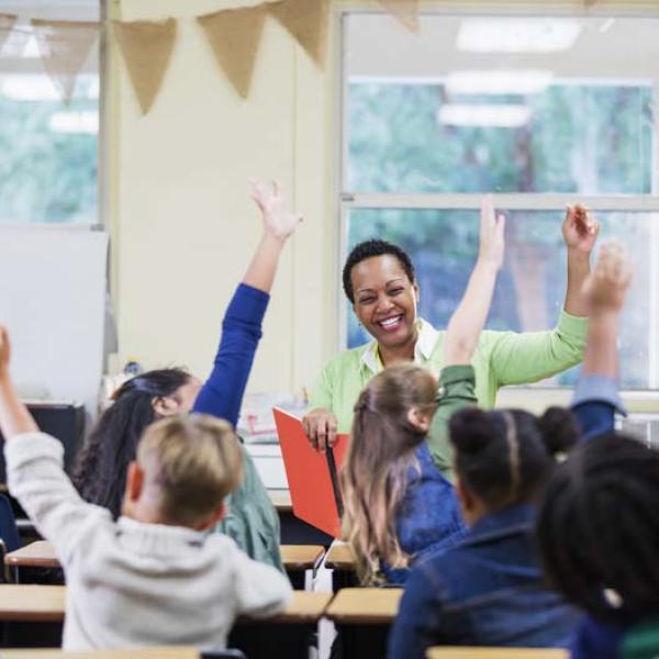 kids raising hands with teacher at front