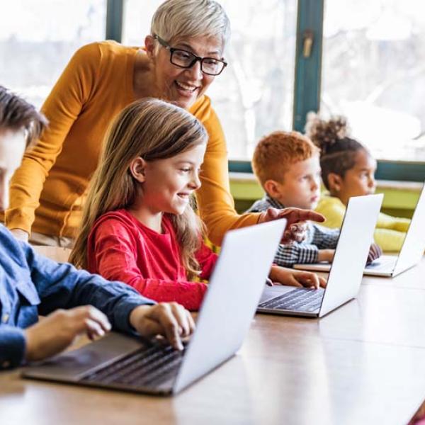 teacher with kids at laptops
