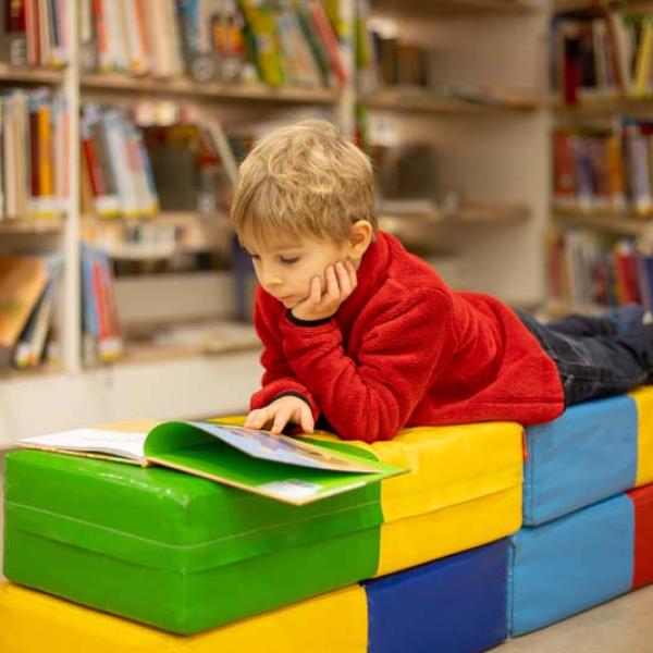 boy reading a book on colorful blocks