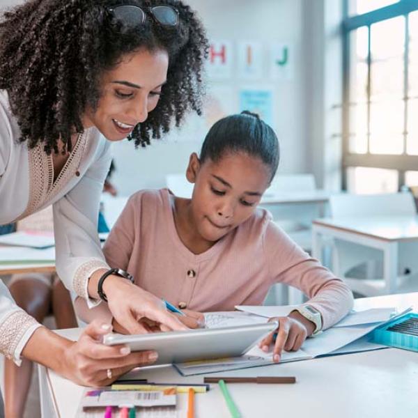 teacher and girl at desk with notebook