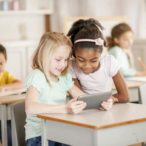 two girls at desk with tablet