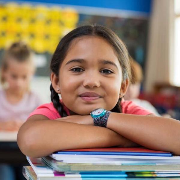 girl with arms crossed on top of books